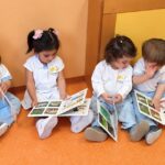Niños de 0 a 3 años ojeando libros en el rincón de lectura de la escuela infantil CEI Xicotets